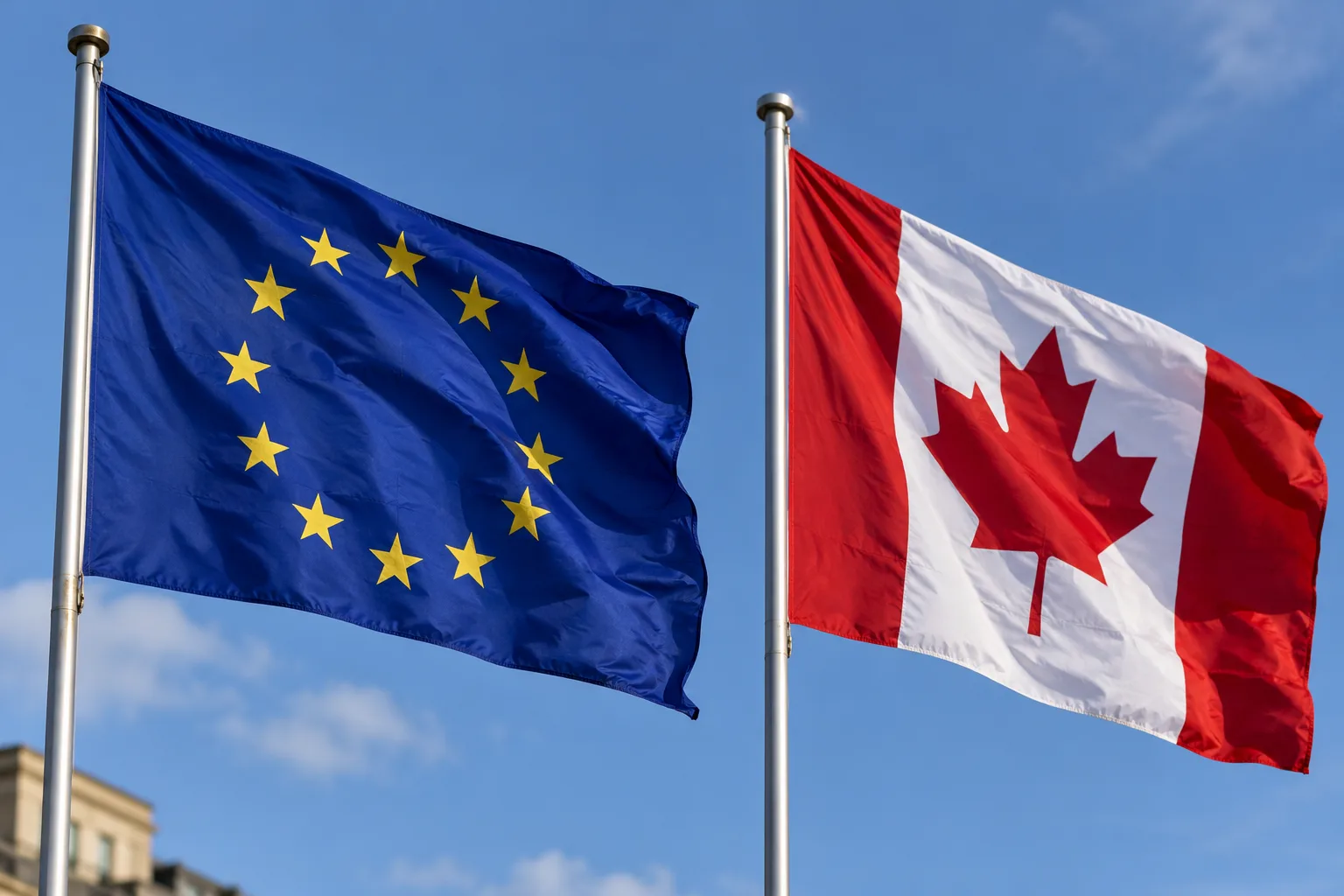 Die Flaggen der Europäischen Union und Kanadas wehen nebeneinander vor blauem Himmel. Das Bild steht symbolisch für die Beziehungen zwischen der EU und Kanada.